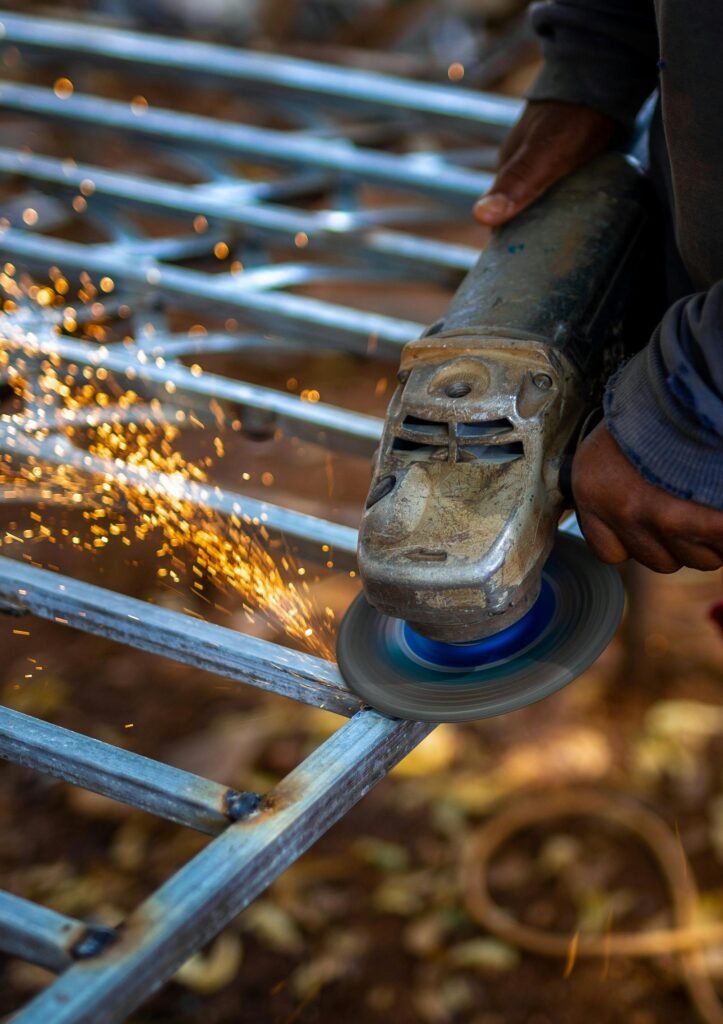 Close-up of a worker using a grinder on metal, creating a shower of sparks.