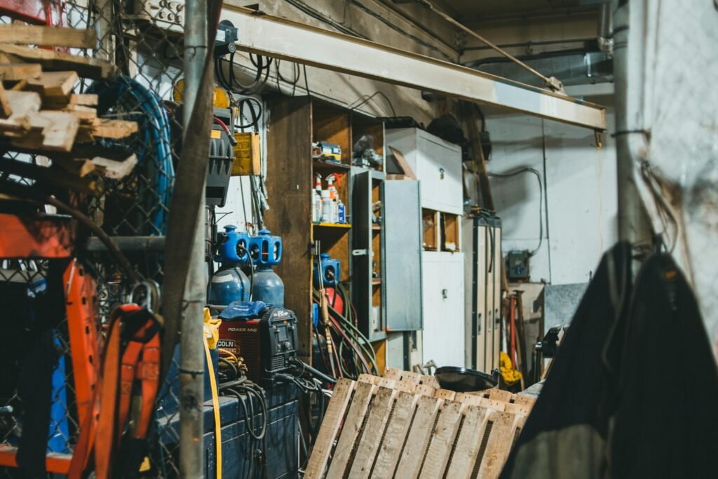 Inside view of a cluttered workshop filled with tools, equipment, and gas cylinders.